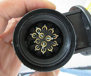 Close-up of the interior of a 13-pin trailer plug showing the brass electrical contacts