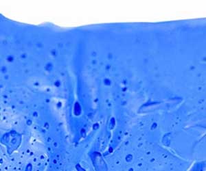 Extreme close-up of the blue car cleaning clay in water, showing its texture and foaming action.