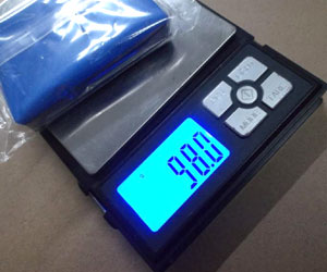 A piece of Professional magic car clean clay is being weighed on a small digital scale, showing a weight of 98 grams.