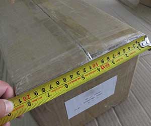 A measuring tape used to measure the dimensions of a large shipping carton for blue clay bars.