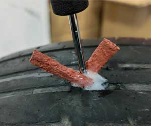 22.OEM Tire Repair plug insertion test, showing the rubber plug being inserted into a tire tread, surrounded by white rubber cement, confirming the basic function check is a pass.