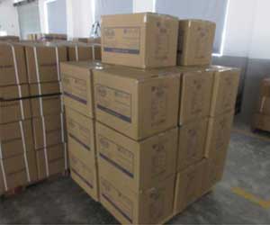 Stacked brown Bike Puncture Kit shipping cartons on a pallet, ready for shipment in a warehouse or factory loading area.