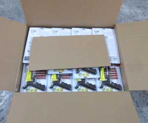 An open shipping carton filled with individually packaged tire repair kits, with a cardboard divider separating the layers.