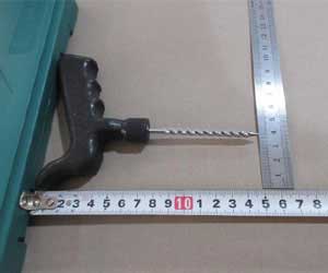 The T-handle reamer tool being measured with a metal ruler and a tape measure to verify its dimensions against specifications.